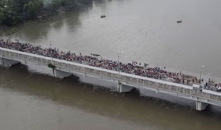 Al menos un millar de migrantes permanecen aparcados en el puente fronterizo en espera de ser atendidos. EFE