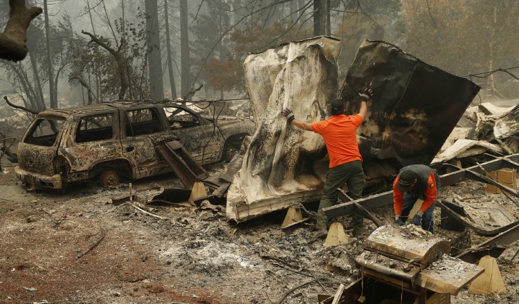 Un socorrista busca restos humanos en un vehículo calcinado en un parque de autos en California. AP