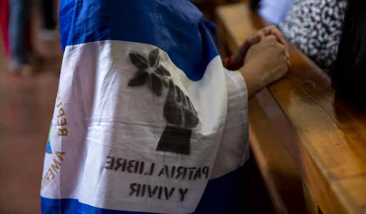 Una joven con una bandera de Nicaragua en la espalda participa de una misa para pedir por la liberación de los presos políticos. EFE