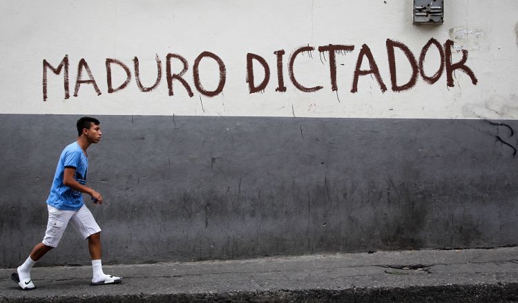 Una persona camina frente a una pared pintada contra el presidente de Venezuela, Nicolás Maduro, en el centro de la ciudad de Caracas. EFE