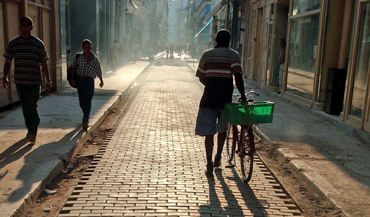 Personas caminan sobre los adoquines en la comercial calle Del Obispo, en La Habana Vieja.   EFE