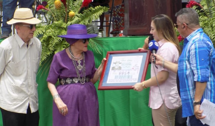 Sheila Lichacz cuando recibe el reconocimiento de la Lotería Nacional de Beneficencia. La Acompaña su esposo John (primero a la izquierda). Foto: Cortesía.