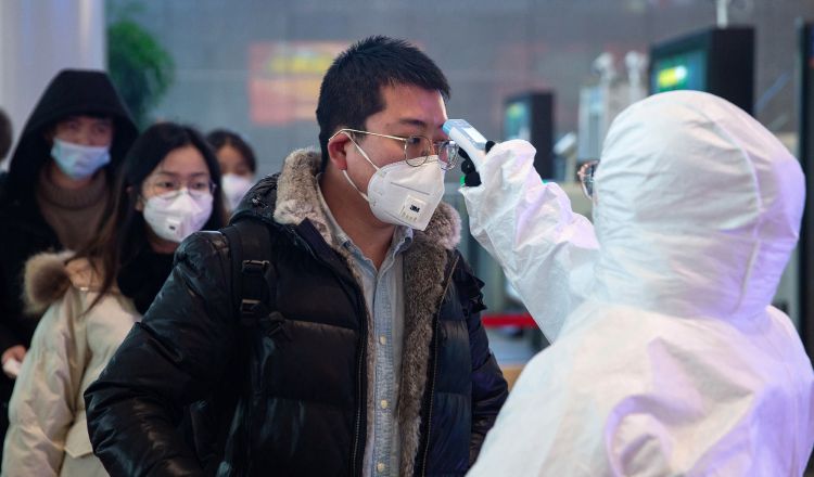 Personal médico chequea la temperatura de una persona en Nanjing, China como medidas de prevención contra el coronavirus. Foto EFE