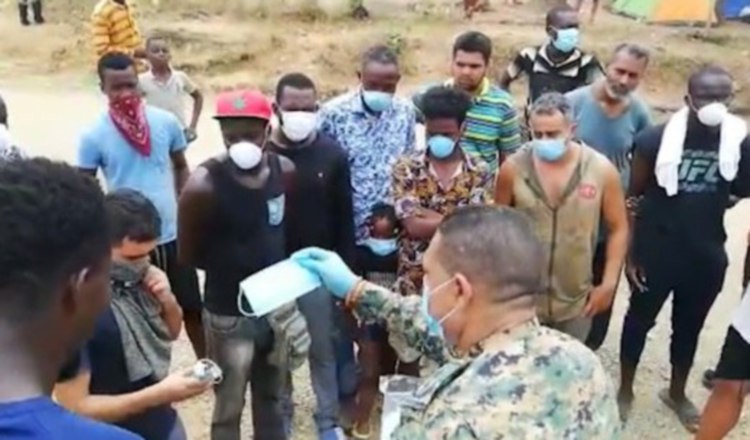 Un agente del Senafront entrega mascarillas a migrantes. Foto EFE