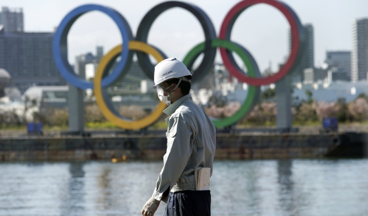 Un hombre trabaja con los anillos olímpicos fe fondo en el distrito de Odaiba en Tokio. Foto:AP