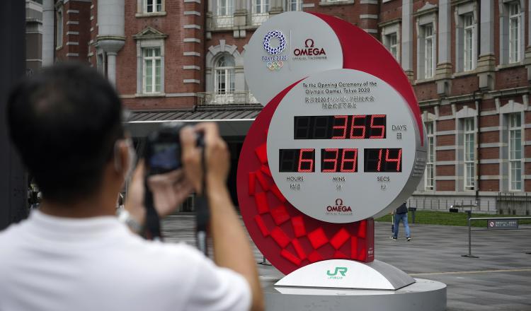 Un afcionado toma una foto del reloj que lleva el tiempo aplazado de los Juegos de Tokio. Foto:EFE
