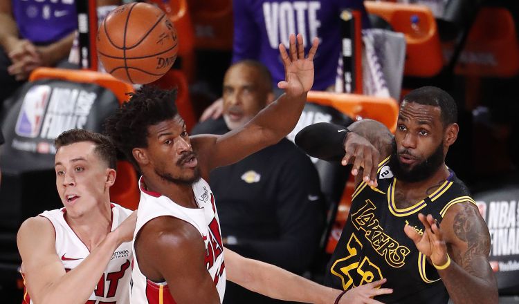 LeBron James realiza un pase de balón, ante la marca  Jimmy Butler de los Heat.  Foto:EFE