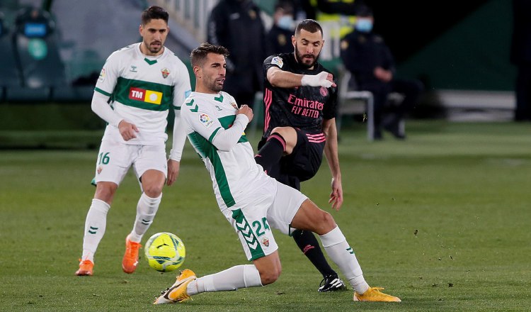 El delantero francés del Real Madrid, Karim Benzema (der.), patea el balón ante el defensa del Elche, Josema. Foto:efe