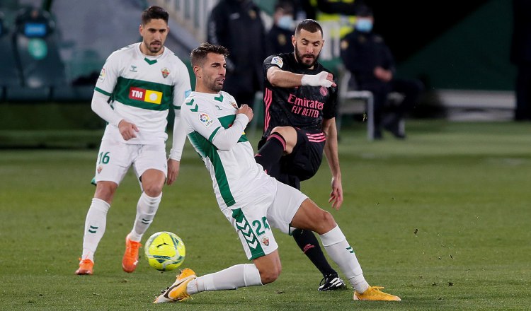 El delantero francés del Real Madrid, Karim Benzema (der.),  patea el balón ante el defensa del Elche, Josema. Foto:efe