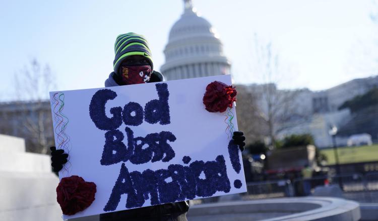 Un hombre sostiene un cartel que dice 'Dios bendiga a América' fuera del Capitolio de los Estados Unidos, en Washington. Foto:EFE