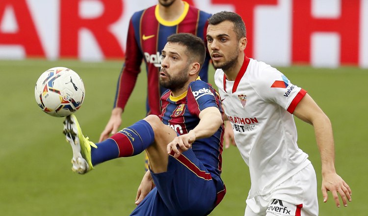El defensa del Barcelona Jordi Alba (izq.) controla el balón ante el centrocampista del Sevilla Joan Jordán  Foto:EFE