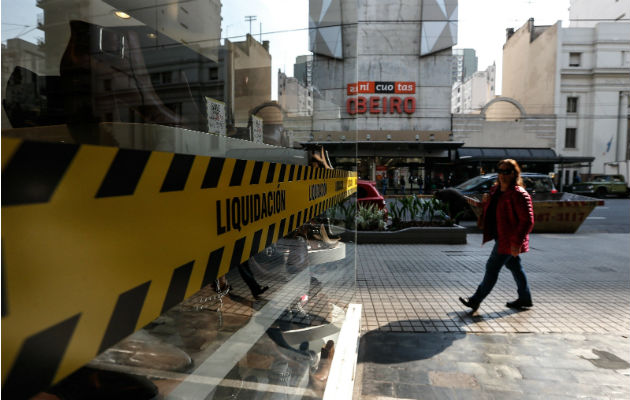 Una mujer pasa frente a un negocio con aviso de liquidación, en Buenos Aires (Argentina). Foto: EFE.