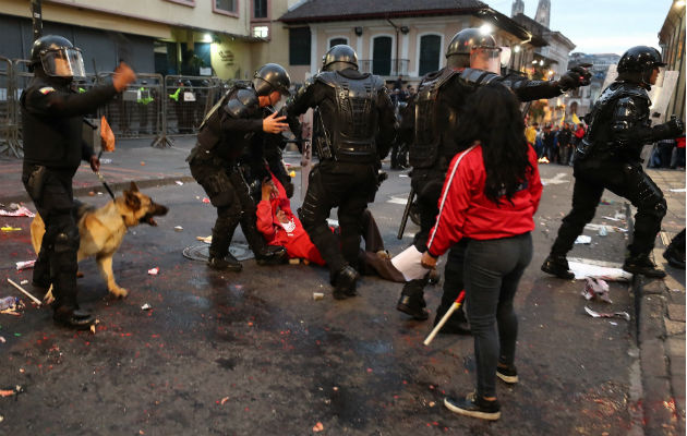 Policías se enfrentan a manifestantes durante una protesta de apoyo a favor del australiano Julian Assange, en Quito. Foto: EFE.