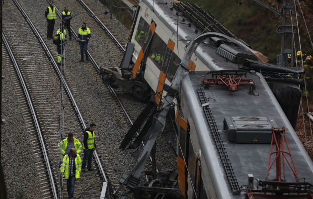 Bomberos y trabajadores de emergencia están parados junto a los vagones descarrilados del tren cerca de Barcelona. EFE