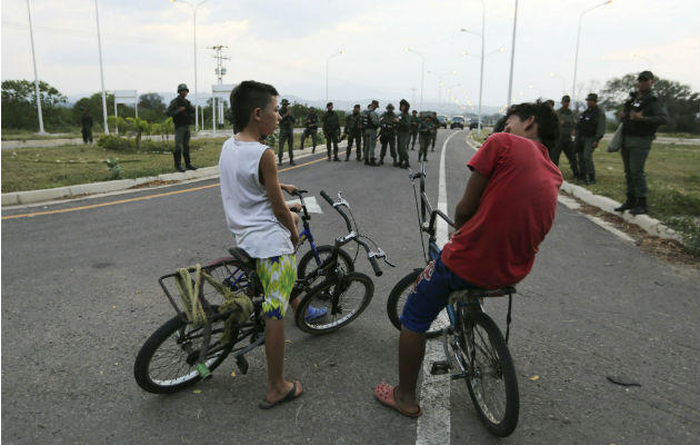 Dos niños en bicicleta frente a soldados venezolanos que bloquean el paso por el puente internacional de Tienditas. Foto: AP