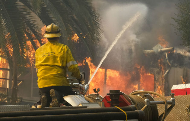 Un bombero echa agua a una casa incendiada en Malibú. Foto: AP.