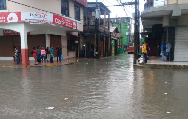 Los residentes se las tienen que ingeniar para poder cruzar la vía por las inundaciones en Colón. 