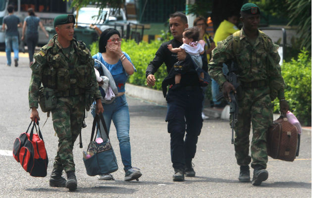 Soldados colombianos acompañan a un policía venezolano (c-d), que carga a su hija, y a su esposa (c-i), luego de desertar, este miércoles en el puente Simón Bolívar, en Cúcuta (Colombia). Foto: EFE.