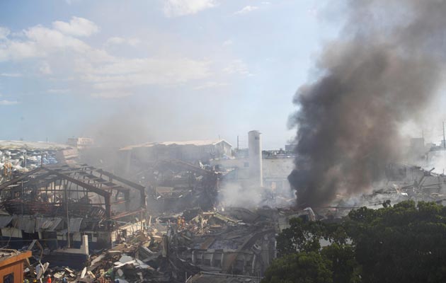 Miembros del cuerpo de bomberos trabajan entre los escombros que dejó una fuerte explosión en una fabrica de plásticos, en el sector Villas Agrícolas, en Santo Domingo. FOTO/EFE