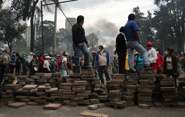 Manifestantes tras una barricada de piedras que bloquea una calle este sábado, en Quito. Foto: EFE.