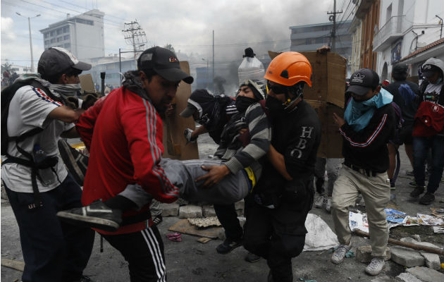 Manifestantes tras una barricada de piedras que bloquea una calle este sábado, en Quito. Foto: EFE.