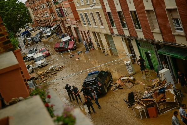 Los residentes caminan en la calle junto a los autos dañados después de las fuertes lluvias en Tafalla, en el norte de España. FOTO/AP