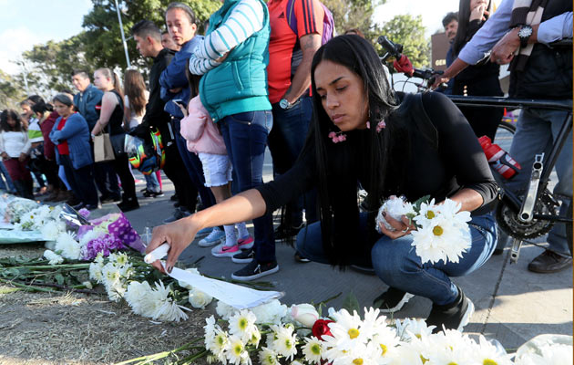 Decenas de personas llevan flores y prenden velas en honor a los policías fallecidos en el ataque de ayer en la Escuela de Cadetes de Policía General Francisco de Paula Santander, en Bogotá. FOTO/EFE