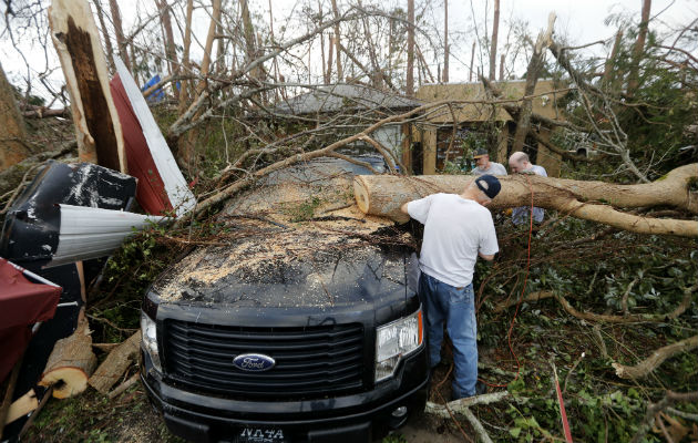 La gente corta un árbol que cae en un vehículo después del huracán Michael en la ciudad de Panamá, Florida. AP 