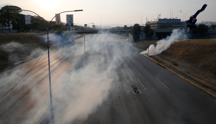 El gas lacrimógeno cubre una carretera vacía junto a la base aérea La Carlota en Caracas. FOTO/AP