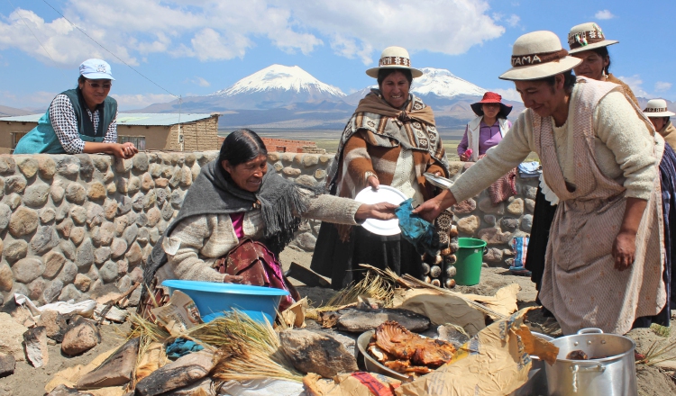 Mujeres de la comunidad Sajama preparando un plato de comida cocinado debajo de la tierra.  EFE/Yolanda Salazar