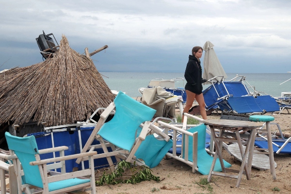 Una mujer camina entre sillas y paraguas que los fuertes vientos y el agua arrasaron en Sozopolis, Chalkidiki, norte de Grecia. FOTO/AP