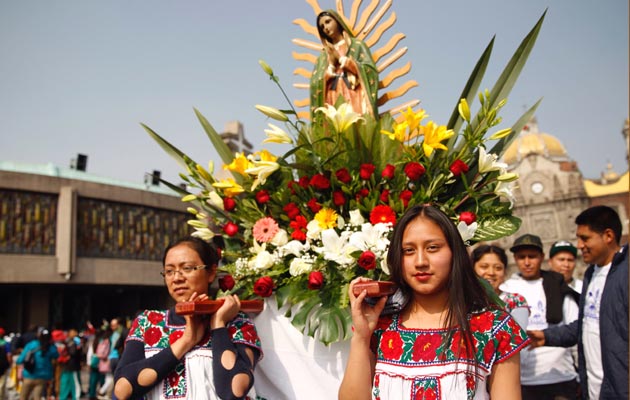 Dos jóvenes cargan una corona de flores con la imagen de la virgen de Guadalupe. FOTO/EFE