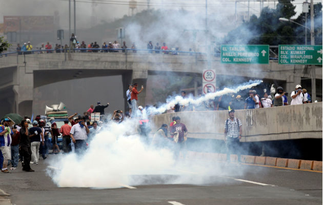 Personas se enfrentan  a efectivos de la Policía hondureña en el segundo día de paro nacional, en Tegucigalpa. EFE