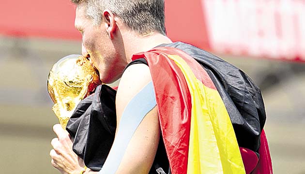 El volante alemán Bastian Schweinsteiger besa la copa.(AP)
