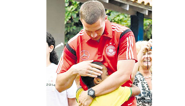 Lukas Podolski abraza a un niño durante su visita a una escuela.(DFB-Team)