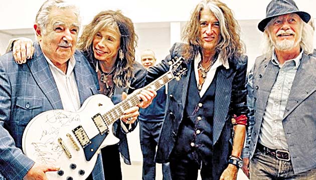 Miembros de la banda Aerosmith le regalan una guitarra eléctrica.