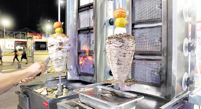 La carne gira y detrás se encuentran las brasas.