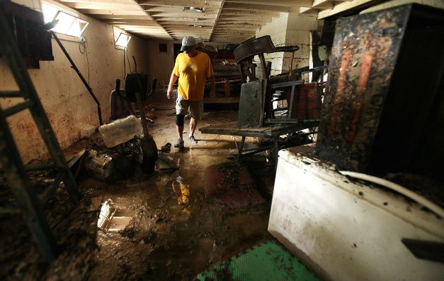 Gene McCarty limpia el piso dañado después de la inundación.(EFE)