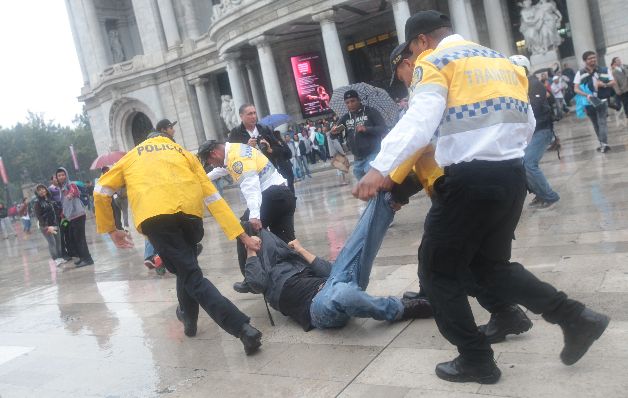 Policías detienen a un joven que violentaba los comercios. / EFE Miles marchan al año de la desaparición de unos 43 estudiantes