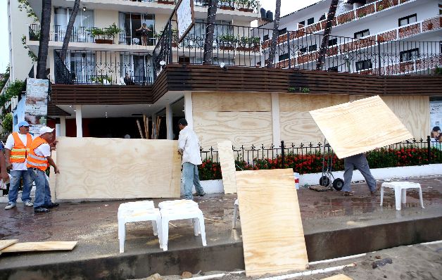 Hombres tapan los vidrios con madera para su protección ante la llegada de