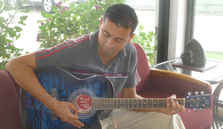 Cantando acompañado de la  guitarra, lleva el pan a su hogar.