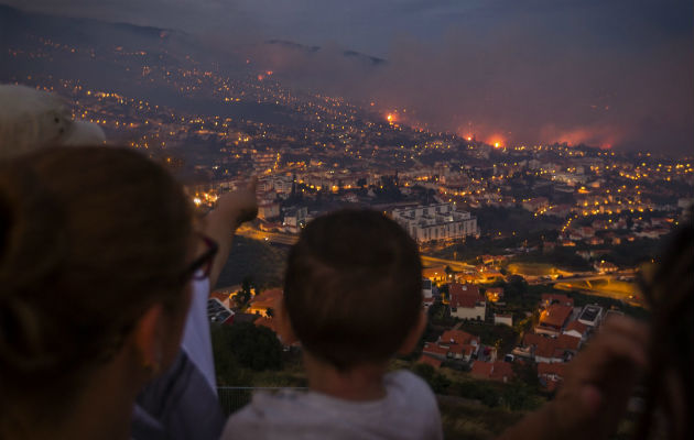 Un grupo de personas observa un incendio forestal en Funchal, Isla Madeira. FOTO:EFE