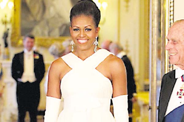 ‘Glamour’: Para la recepción, celebrada en el 2011, en el palacio de Buckingham, Michelle Obama escogió este modelo en blanco del diseñador Tom Ford, de escote cruzado, al que le añadió unos guantes.