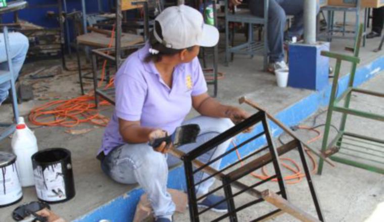 Voluntaria reparando y pintando las sillas de algunos colegios. /Foto Cortesía