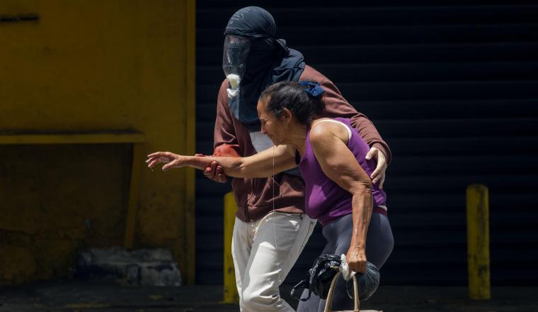 Manifestante auxilia a una señora mayor en medio de protesta. Manifestante auxilia a una señora mayor en medio de protesta.