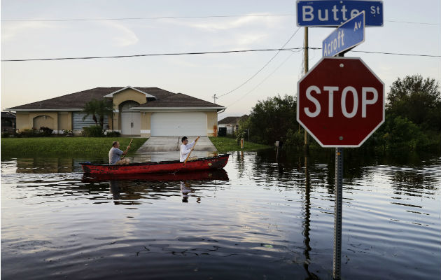 Padre e hijo a través de su vecindario inundado tras el huracán Irma. Foto: AP.  