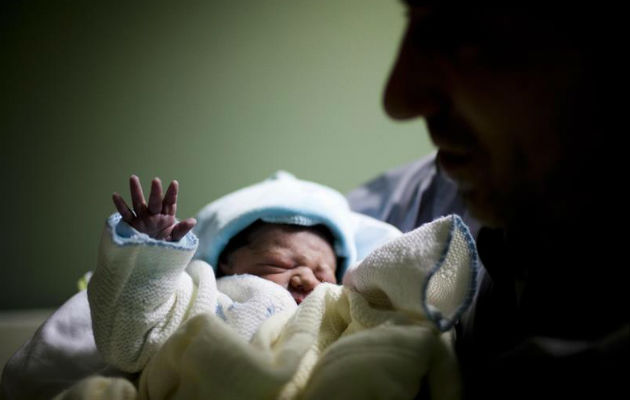 Un hombre sostiene a su hijo recién nacido.