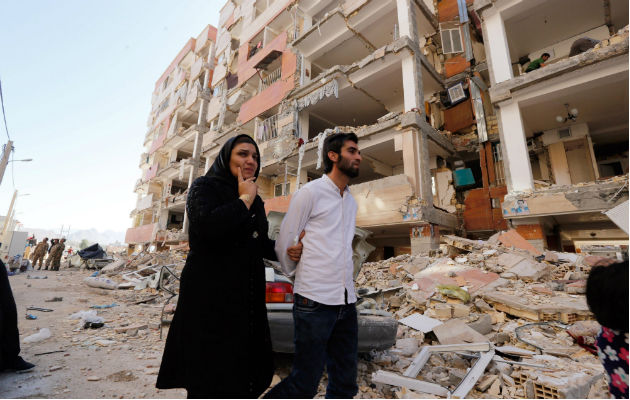 Una pareja camina entre los restos de los edificios. Foto: EFE 