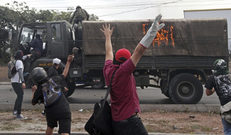 Un soldado y un conductor abandonan su vehículo en llamas. /Foto AP