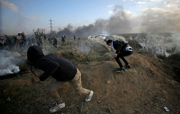 Unos jóvenes palestinos corren para resguardarse de los ataques. Fotos: EFE